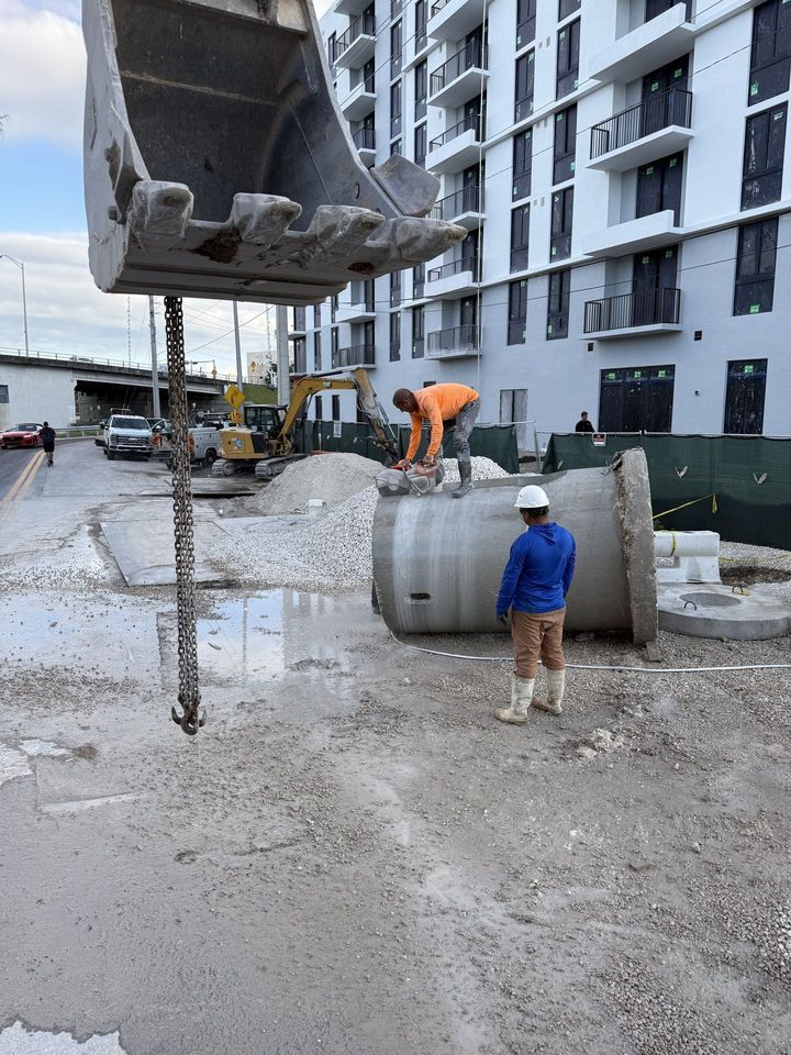 Crew handling precast pipe beside a new building